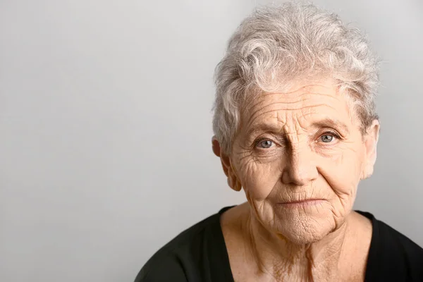 Retrato de mulher idosa em fundo cinza — Fotografia de Stock