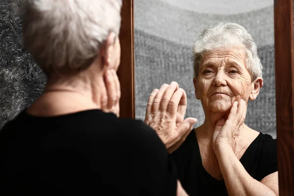 Senior woman looking in mirror — Stock Photo, Image