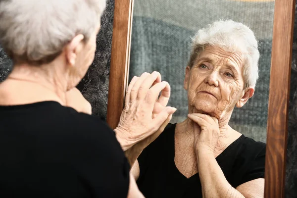 Senior woman looking in mirror — Stock Photo, Image