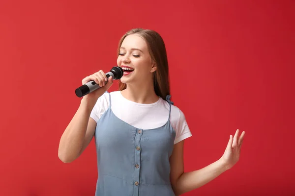 Renkli arka planda mikrofon ile güzel kadın şarkıcı — Stok fotoğraf