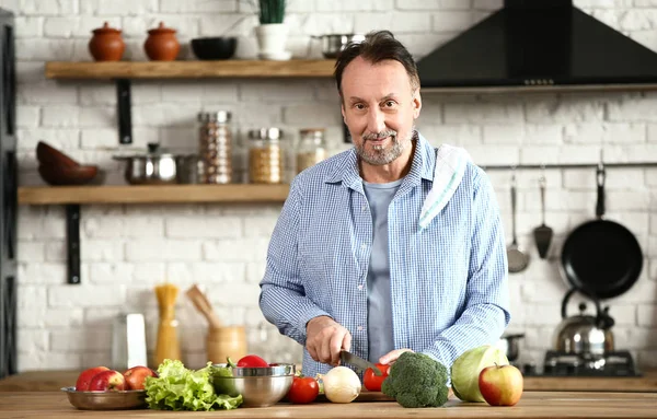 Stilig mogen man förbereder sallad i köket — Stockfoto