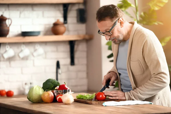 Jóképű érett férfi készül saláta konyhában — Stock Fotó
