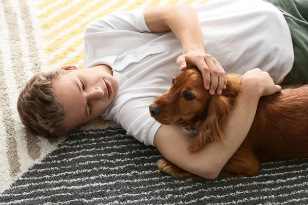 Teenage boy with cute dog lying on carpet at home — Stock Photo, Image