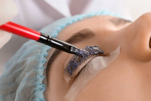 Young woman undergoing procedure of eyelashes dyeing and lamination in beauty salon, closeup — Stock Photo, Image