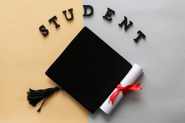 Mortar board with diploma and word STUDENT color background. Concept of high school graduation