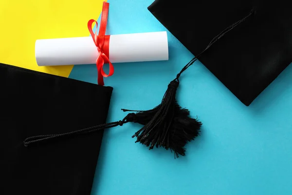 Mortar boards with diploma on color background. Concept of high school graduation — Stock Photo, Image