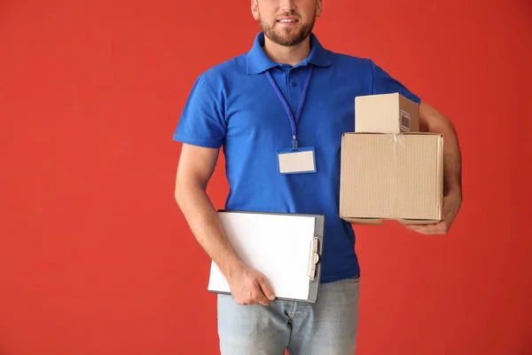 Renkli arka plan üzerinde kutuları ve panosu ile Yakışıklı teslimat adam — Stok fotoğraf