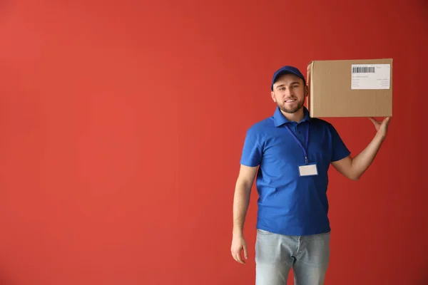 Snygg leverans man med låda på färg bakgrund — Stockfoto