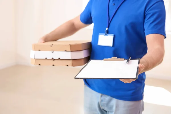 Entrega homem com caixas de pizza e área de transferência dentro de casa — Fotografia de Stock