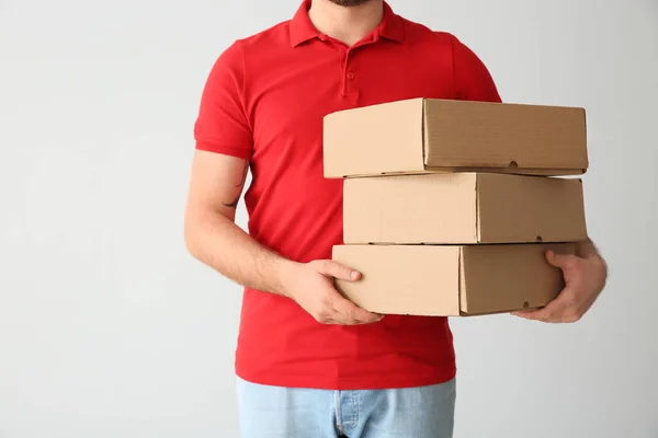 Delivery man with boxes on light background