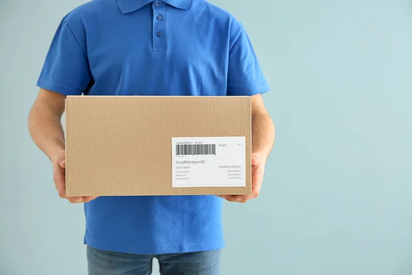 Delivery man med box på färg bakgrund — Stockfoto