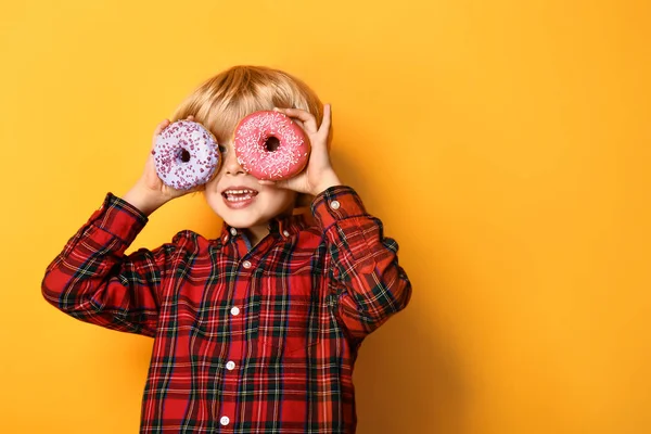 Šťastný malý chlapec s chutnými koblihami na barevném pozadí — Stock fotografie