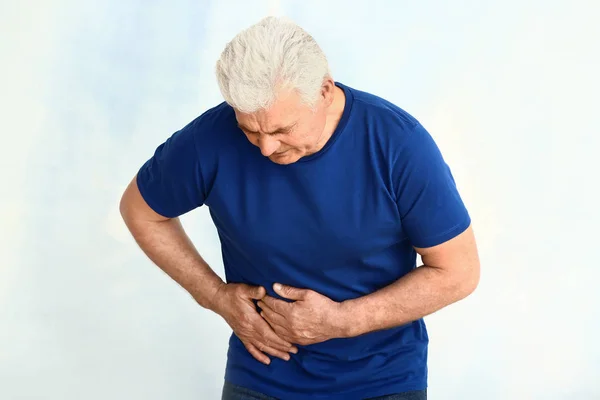 Reifer Mann mit urologischer Erkrankung vor hellem Hintergrund — Stockfoto