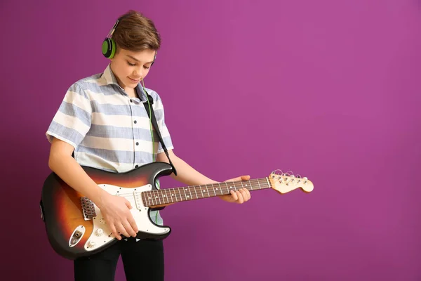 Teenage boy playing guitar against color background — Stock Photo, Image