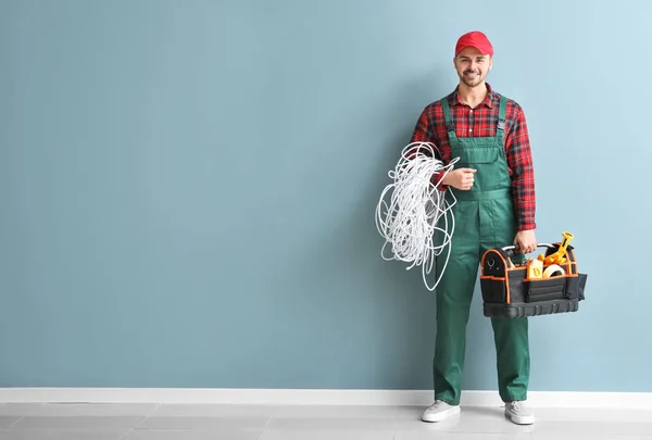 Electricista masculino con kit de herramientas cerca de la pared de color — Foto de Stock