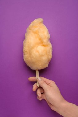 Renkli arka planda lezzetli pamuk şeker ile kadın el