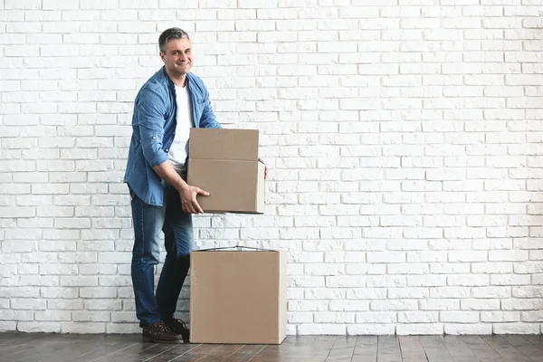 Beyaz tuğla duvara yakın hareketli kutuları ile Yakışıklı olgun adam — Stok fotoğraf