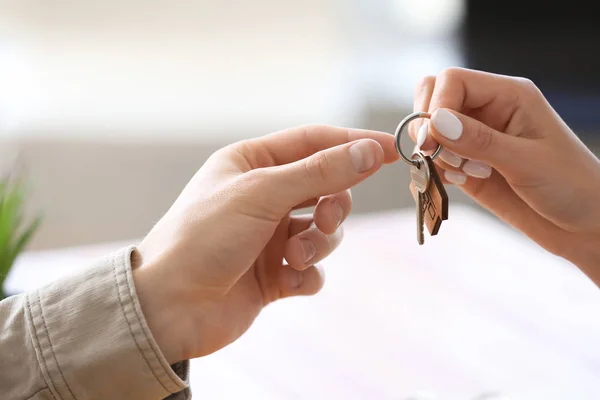 Agente imobiliário dando chave de casa nova para jovem no escritório — Fotografia de Stock