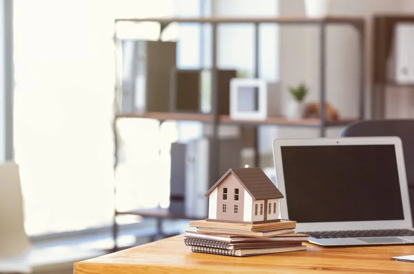 Modelo de casa con portátil en la mesa de agente de bienes raíces en la oficina —  Fotos de Stock