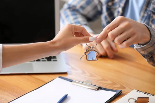 Real estate agent giving key from new house to young man in office — Stock Photo, Image