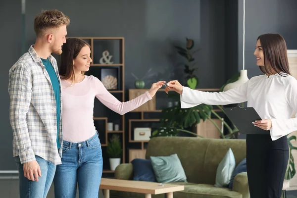 Real estate agent giving a key from new house to young couple — Stock Photo, Image