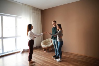 Emlakçı yeni evden genç çifte anahtar veriyor.