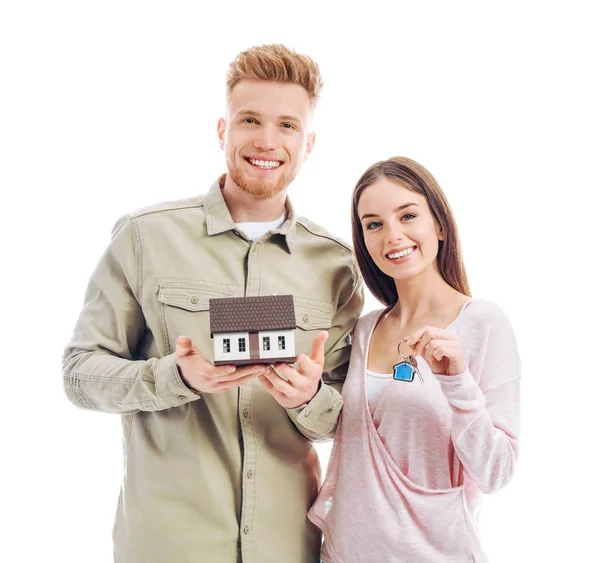 Junges Paar mit Hausmodell und Schlüssel aus dem neuen Zuhause auf weißem Hintergrund — Stockfoto