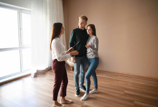 Agente imobiliário mostrando jovem casal uma nova casa — Fotografia de Stock