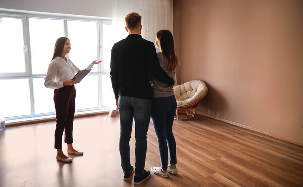 Агент по недвижимости показывает молодой паре новый дом
