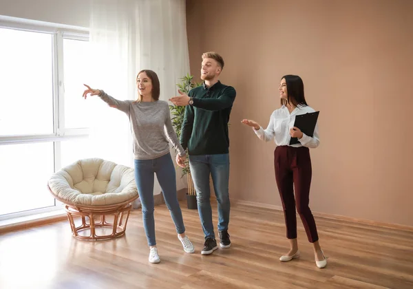 Real estate agent showing young couple a new house — Stock Photo, Image