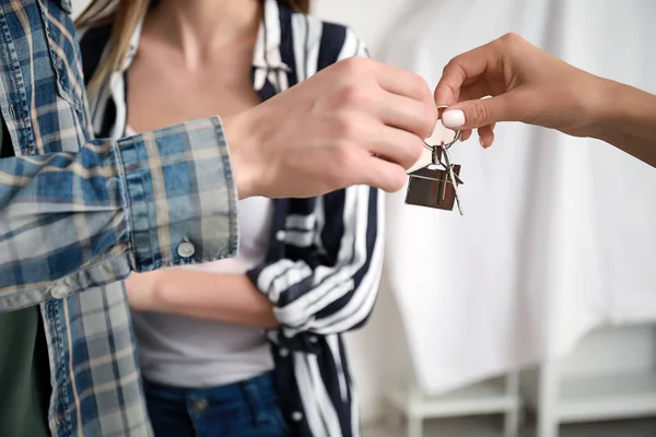 Inmobiliaria dando una llave de casa nueva a pareja joven — Foto de Stock