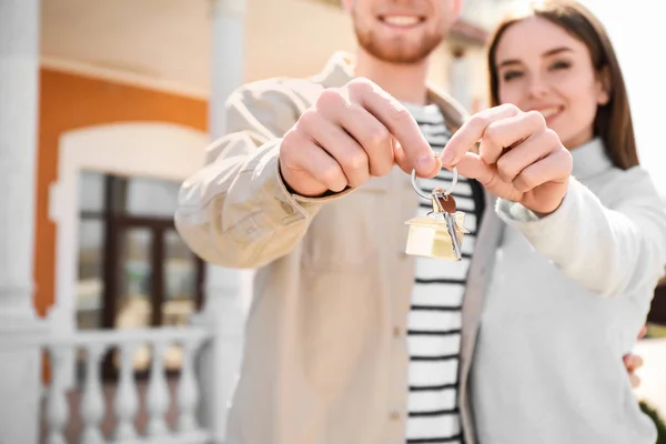 Pareja joven con llave cerca de su nueva casa al aire libre — Foto de Stock