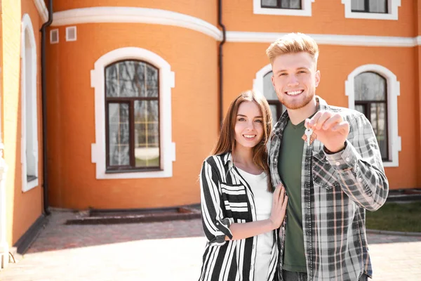 Young couple with key near their new house outdoors — Stock Photo, Image