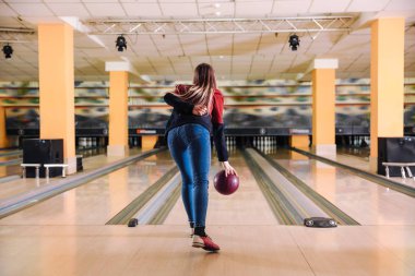 Kulüpte bowling oynayan genç bir kadın.