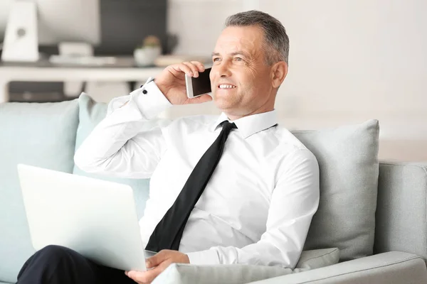 Knappe volwassen zakenman praten telefonisch tijdens het werken op laptop in Office — Stockfoto