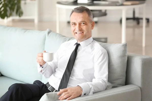 Przystojny dojrzały biznesmen picie kawy w biurze — Zdjęcie stockowe