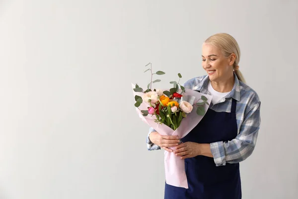 Florista feminina com buquê no fundo claro — Fotografia de Stock