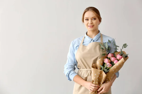 Vrouwelijke bloemist met boeket op lichte achtergrond — Stockfoto
