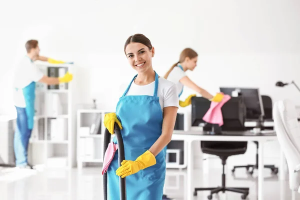 Janitor feminino com aspirador de pó no escritório — Fotografia de Stock