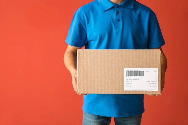 Delivery man with box on color background — Stock Photo, Image