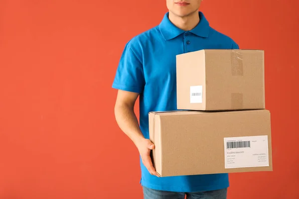 Liefermann mit Schachteln auf farbigem Hintergrund — Stockfoto