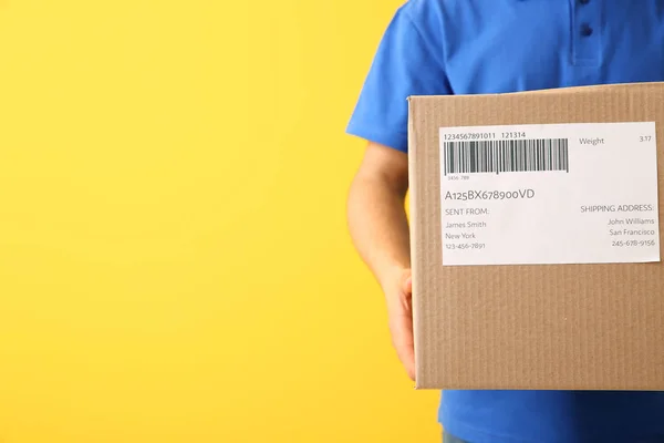Delivery man with box on color background, closeup