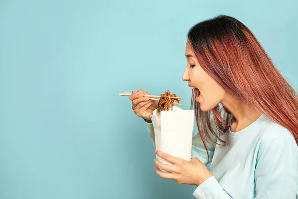 Asian woman eating delicious Chinese food on color background — Stock Photo, Image