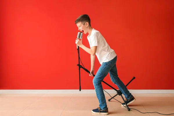 Menino adolescente com microfone cantando contra a parede de cores — Fotografia de Stock