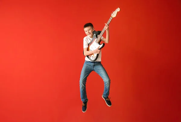 Хлопчик-підліток грає на гітарі проти кольорової стіни — стокове фото
