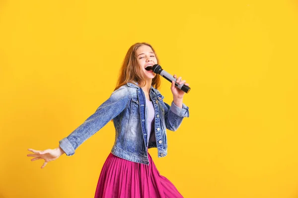 Adolescente com microfone cantando contra fundo de cor — Fotografia de Stock