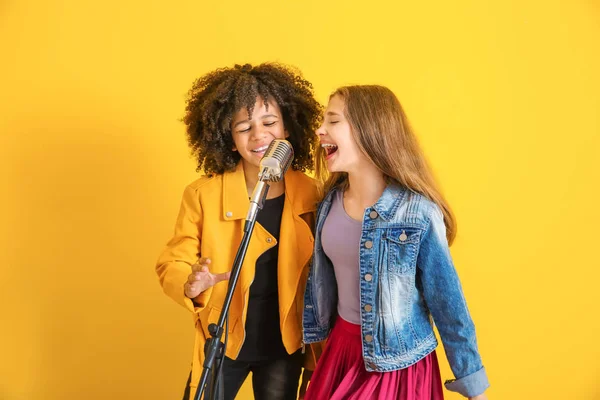 Ragazze adolescenti con microfono che cantano sullo sfondo di colore — Foto Stock