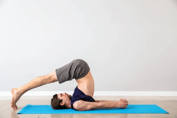 Sporty man practicing yoga indoors — Stock Photo, Image