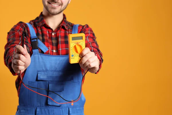 Male electrician with multimeter on color background — Stock Photo, Image