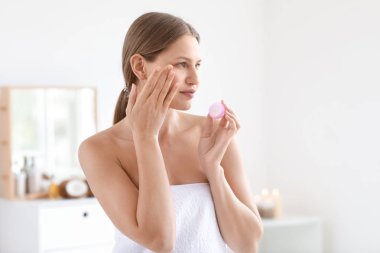 Evde krem uygulayarak güzel genç kadın